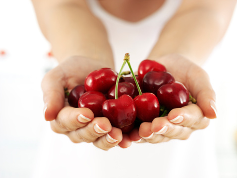 Fresh red cherries fruit in bowl on a concrete background