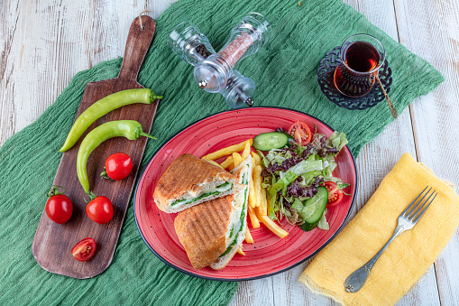 Grilled and pressed toast with smoked cheese, tomato and lettuce served on wooden background.
