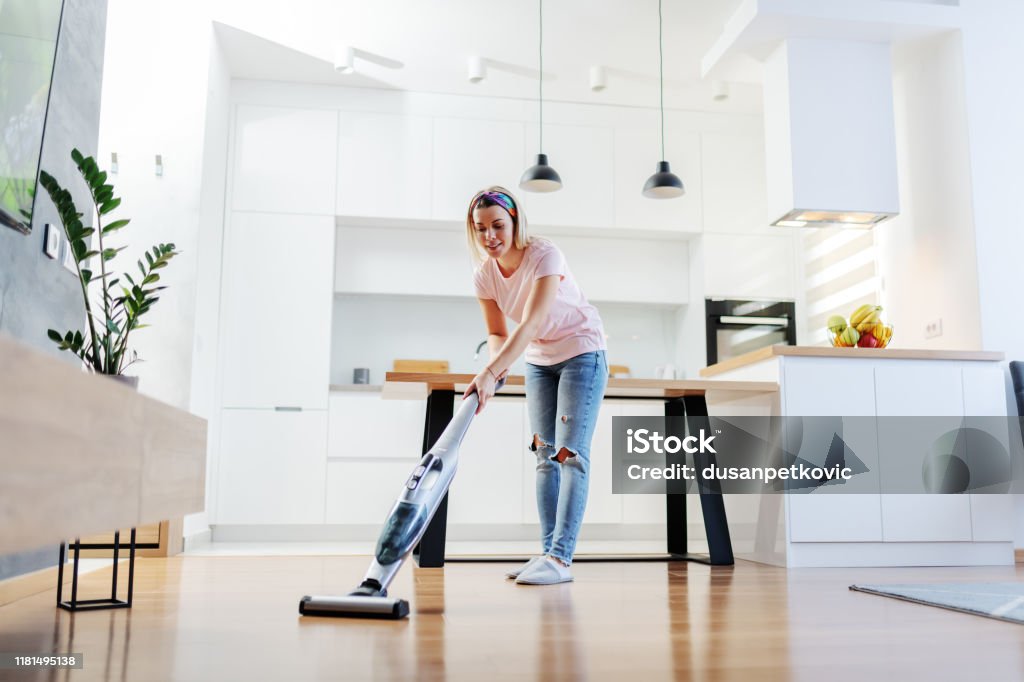Volle Länge der würdigen kaukasischen blondehausfrau mit Dampfer Boden im Wohnzimmer zu reinigen. - Lizenzfrei Staubsauger Stock-Foto