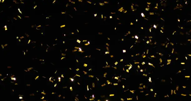 Confetti fired in the air during a party. Only confetti on black background of the night. Falling metallic glitter foil confetti multicolor in black background.