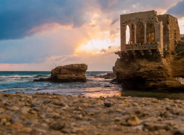 Dramatic sunset by the sea with ancient ruins in the background in Batroun, Lebanon
