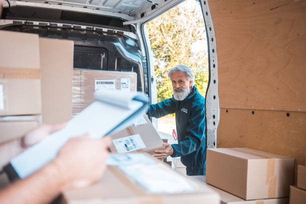 istock Two people unloading the delivery van filled with packages 1181499557