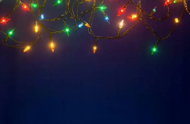 Photo of Christmas lights on blue background with copy space