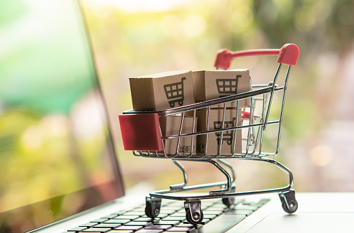 Shopping online concept - Parcel or Paper cartons with a shopping cart logo in a trolley on a laptop keyboard. Shopping service on The online web. offers home delivery.