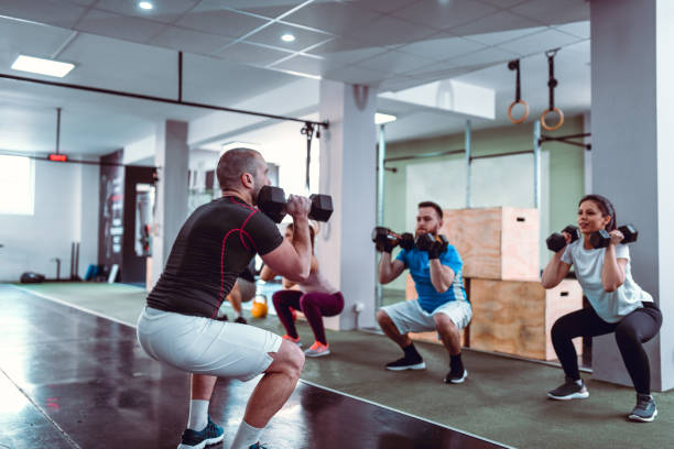 istock Dumbbell Crouches By Athletes In Gym 1181504256