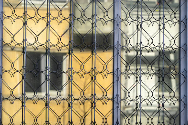 Openwork metal mesh with heart shapes on the window. There are grid reflections on the window glass