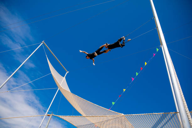 istock Trapeze artists swinging together in the blue sky 1181519081