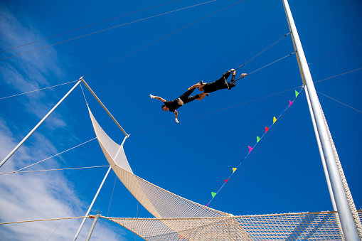 Trapeze artists swinging together in the blue sky