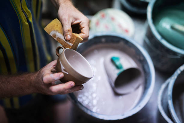 Unrecognizable man glaze at a ceramic cup in a studio.