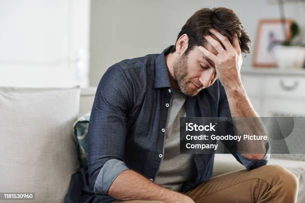 Man Sitting Alone At Home Looking Sad And Distraught Stock Photo - Download Image Now