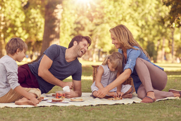 familia riendo teniendo un picnic juntos en el verano - women looking over shoulder people cute fotografías e imágenes de stock
