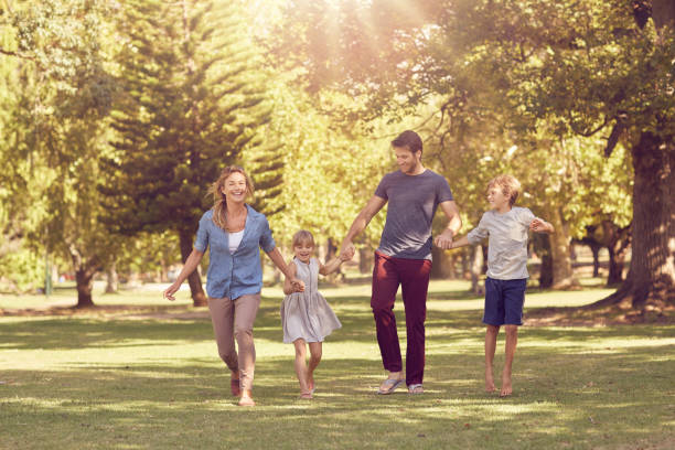istock Smiling family holding hands and walking through a park 1181533704