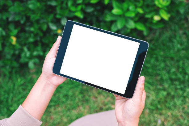 istock a woman holding black tablet pc with blank white desktop screen in the park 1181536718
