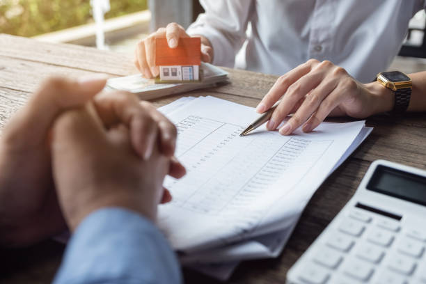 darlehensvertrag, immobilienmakler oder bankangestellter beschreibt die darlehenszinsen für den kunden, zusammen mit darlehensdokumenten mit einem wohn-stil-stift und einem replik-geld auf einem holztisch. - gebühr stock-fotos und bilder