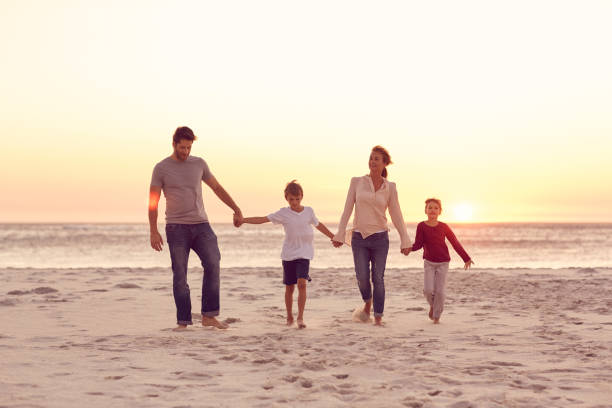 istock Smiling family walking on a beach holding hands at sunset 1181542321