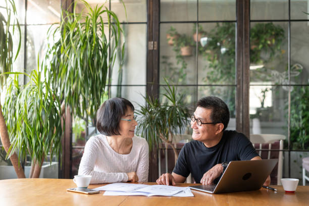 Asian couple talking about buying a new house Asian couple talking about buying a new house. face to face stock pictures, royalty-free photos & images
