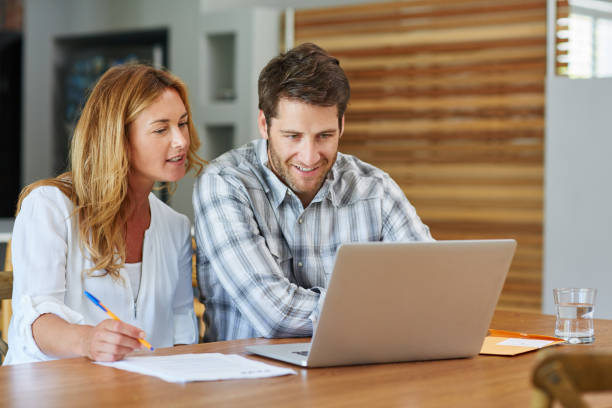 istock Smiling couple doing online banking together at home 1181543480
