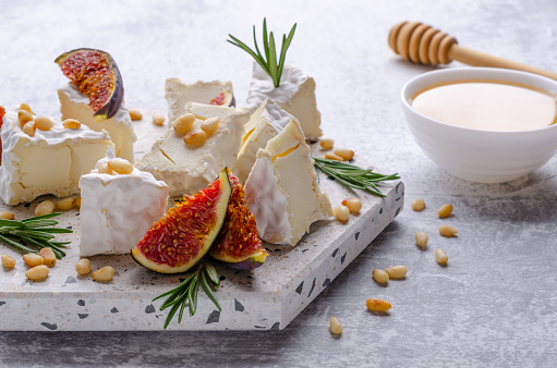 Cheese with white mold with figs, nuts and honey on a slate background. Selective focus.