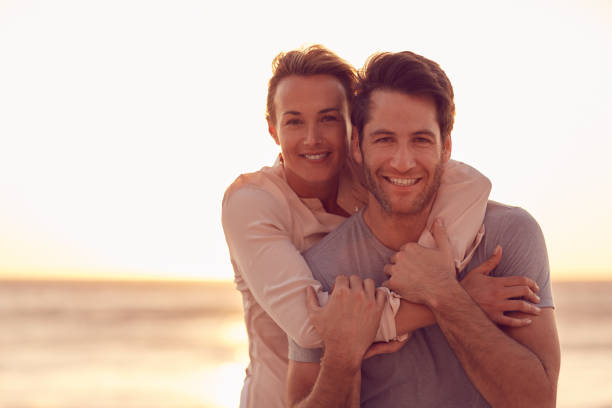 istock Smiling wife hugging her husband on a beach at dusk 1181544470