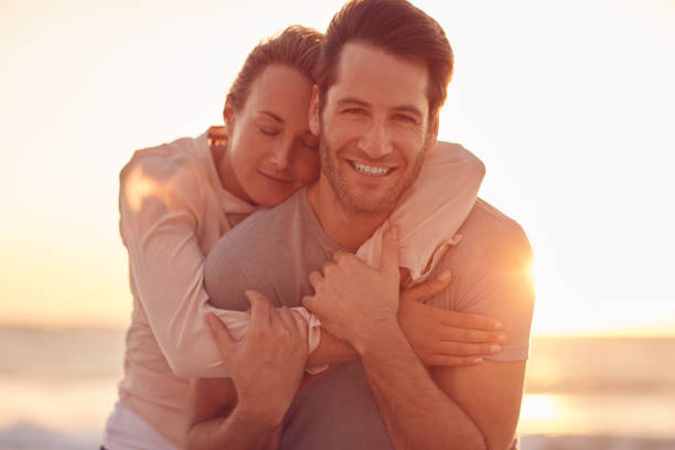 istock Smiling wife hugging her husband on a beach at sunset 1181544494