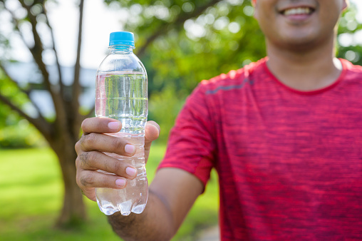 Young fitness man runner  drinking bottle of water.