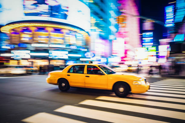 taxi giallo che attraversa midtown manhattan - yellow taxi foto e immagini stock