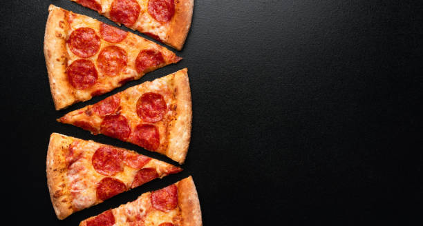 istock Pepperoni pizza slice on black slate background 1181549482