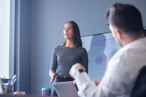 Woman conducting a conference in the boardroom Woman of Latin ethnicity between 25-35 years is at work conducting a conference for her co-workers in the boardroom latin script stock pictures, royalty-free photos & images