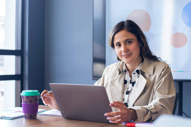 Portrait of Woman working on a laptop in the boardroom Leader woman of latin ethnicity aged 35-45 years is working alone on a laptop in the boardroom latin script stock pictures, royalty-free photos & images