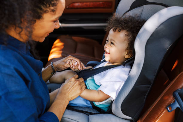 母親説明幼兒被扣到汽車座椅的側視圖 - 嬰兒安全座椅 圖片 個照片及圖片檔