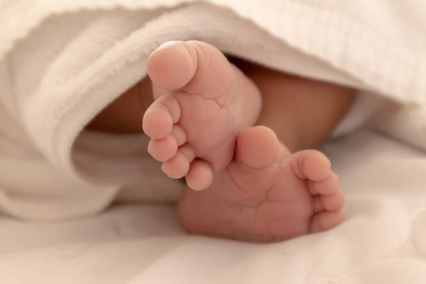生後数ヶ月の新生児の足 白いマットレスの上で快適に眠っている就寝時、子供の脳は働きます。メモリブーストと学習構築のスキルを強化するには - comfortably ストックフォトと画像