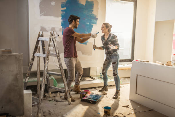 full length of happy couple having fun while painting their walls. - repairing apartment home improvement painting imagens e fotografias de stock