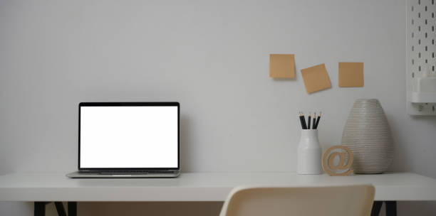 istock Open laptop computer in minimal workplace with ceramic vase and office supplies 1181559852
