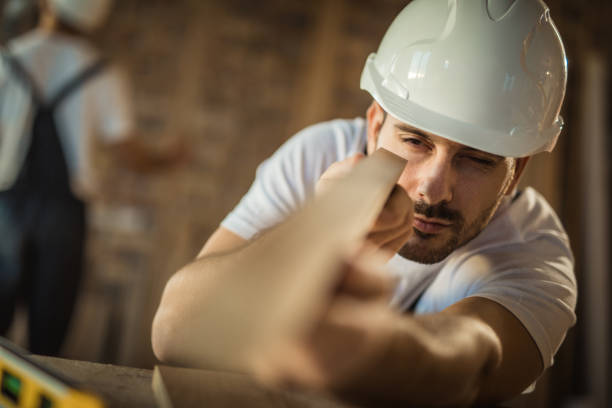 Young carpenter examining if everything is ok with wooden plank during home improvement process.