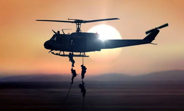 Military commandos helicopter drops during sunrise