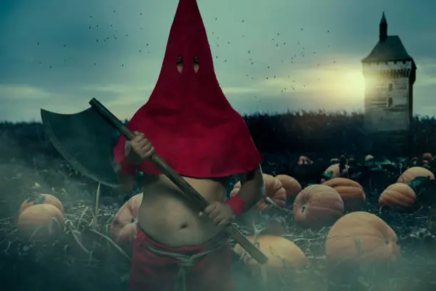 Executioner wearing red cap standing in front of field of pumpings