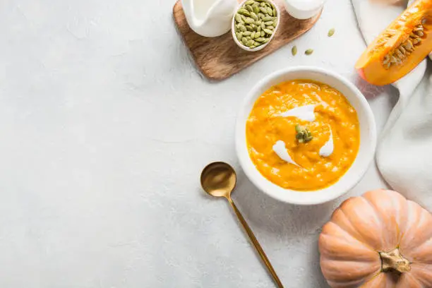 Photo of Pumpkin soup with cream on grey stone background. Copy space. Top view.