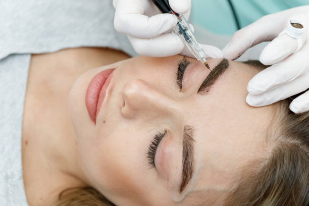 istock Permanent makeup, tattooing of eyebrows. Cosmetologist applying make up 1181573193