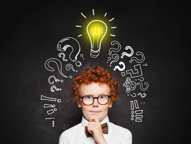 istock Idea concept. Cute young boy student with question marks and light bulb 1181574459