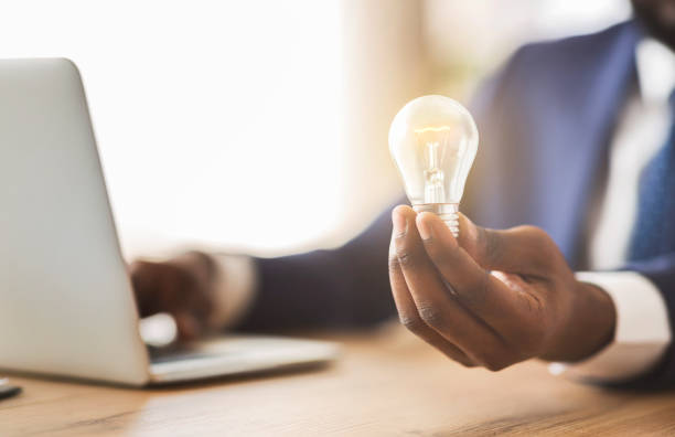 istock Businessman holding illuminated light bulb, sitting in office 1181575793
