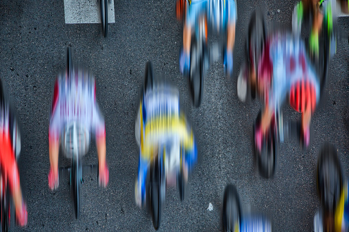 Abstract aerial blurred image of cyclists riding in the pleoton at full speed on an asphalt road.