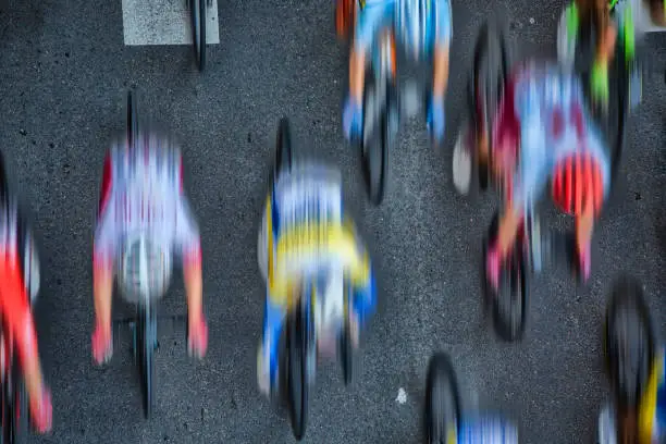 Abstract aerial blurred image of cyclists riding in the pleoton at full speed on an asphalt road.
