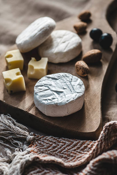 寒い秋と冬の季節のためのファームチーズ。若いカマンベール、マスダム、トミノとブドウとアーモンド - tomino ストックフォトと画像