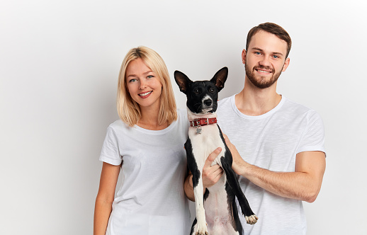 positive happy couple with dog posing to the camera isolated over white background, close up portrait, studio shot. family with favourite pet. lifestyle