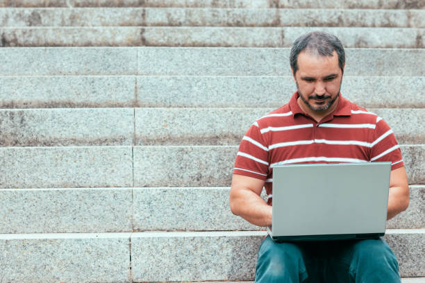istock man sitting on staircase outside and working on laptop. 1181588729