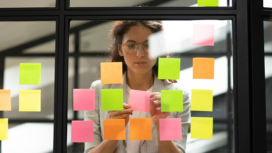 Mujer empresaria creando una lista de tareas usando notas adhesivas multicolores photo