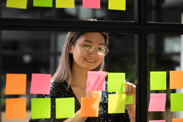 istock Asian businesswoman attached on glass sticky notes writes creative ideas 1181590462