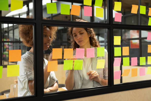 istock Diverse business women writing ideas on sticky notes working together 1181590535