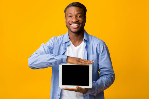 istock Positive Afro Man Showing Blank Tablet Screen, Yellow Background, Mockup 1181592007