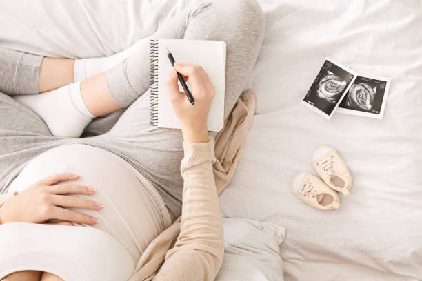 istock Pregnant woman preparing for labor, sitting on bed with notebook 1181594416